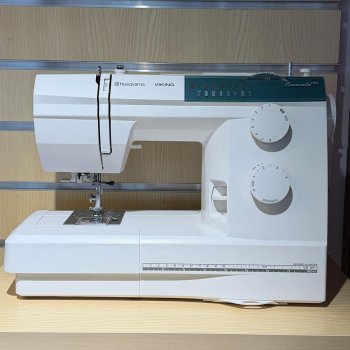 Begagnad symaskin Husqvarna Viking Emerald 116 står på hylla mot en trävägg