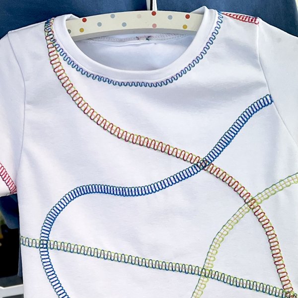 Snygga dekorativa coversömmar sydda på en Baby Lock Primo på en barntröja