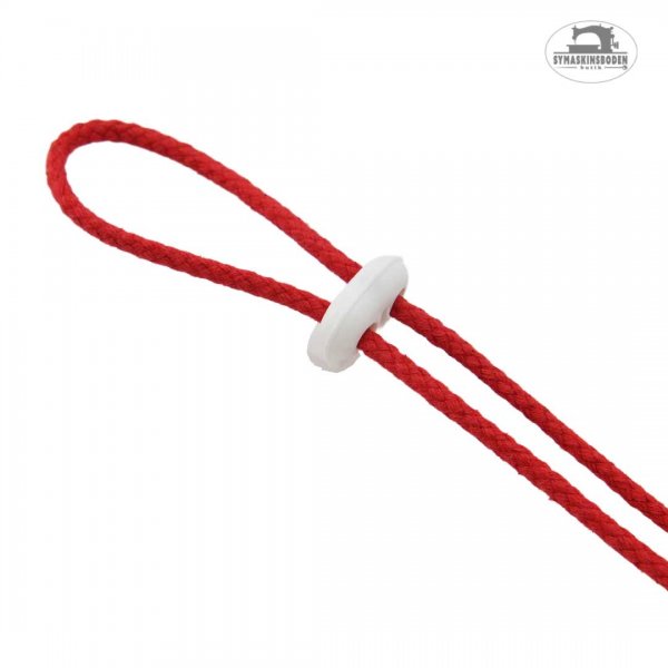 En vit snörstopp med två hål som är påträtt på ett rött snöre.