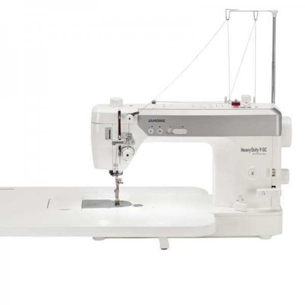 Janome HD9 QCP; vit semi-industriell raksömsmaskin med monterat sybord, knälyft och trådstativ för stora koner.