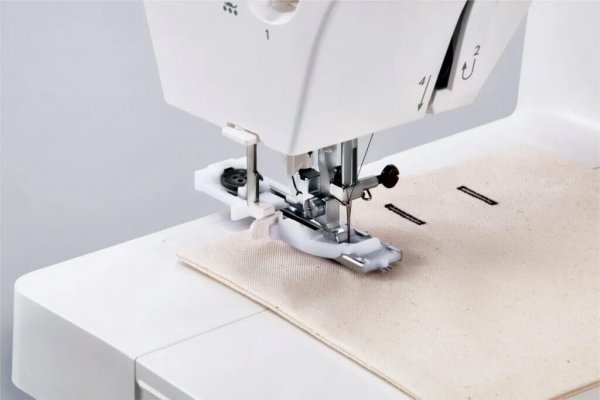 Närbild av syområdet på Janome 1522BG Blue Grey under pågående sömnad av ett automatiskt 1-stegsknapphål på ljust tyg med den mo