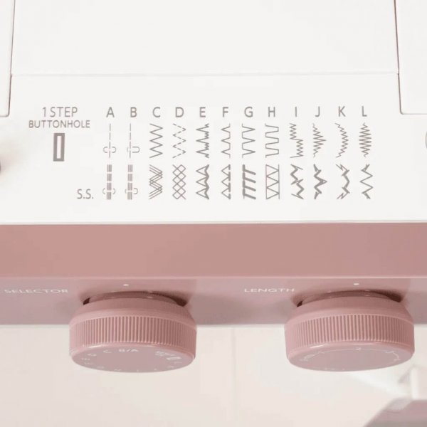 Närbild på den tryckta sömöversikten på maskinkroppen till Janome 1522SP Smokey Pink, som visar diagramsymboler för nyttosömmar,