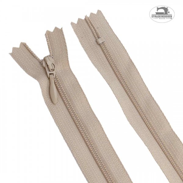 En 25 cm lång dragkedja i färgen beige som passar kjolar och klänningar.